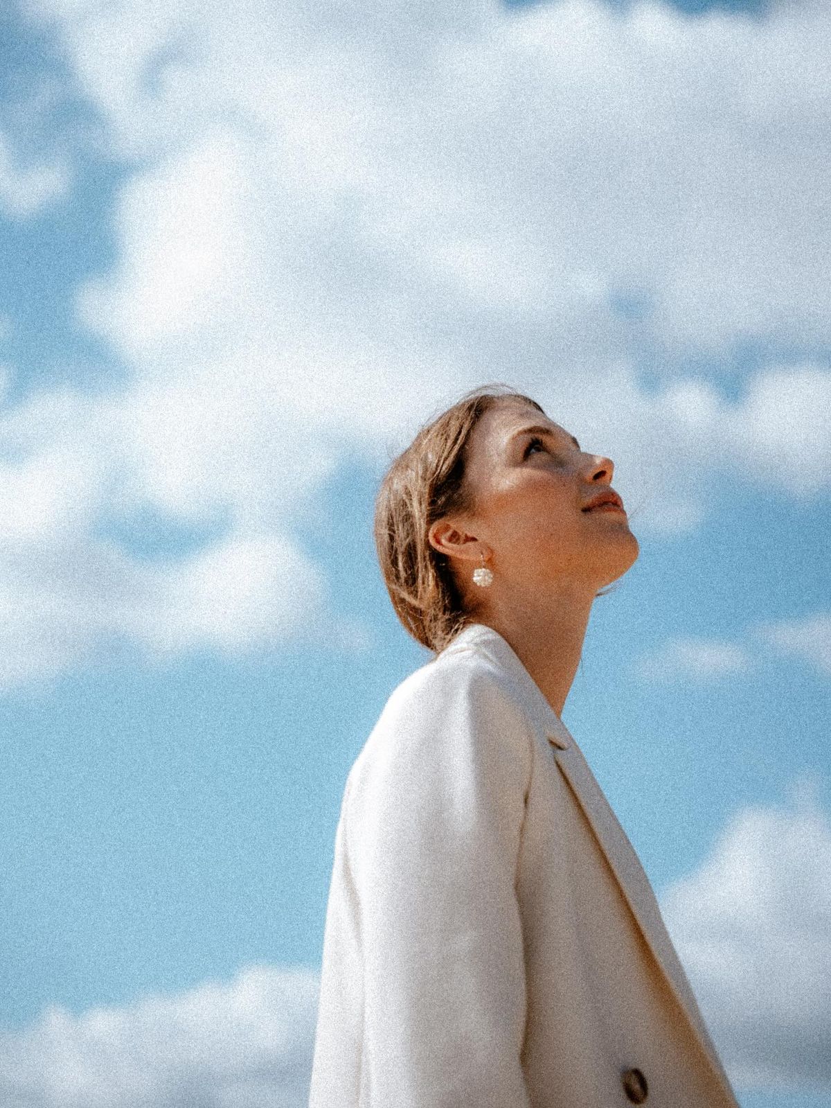 Student in a white coat looking up at the clouds